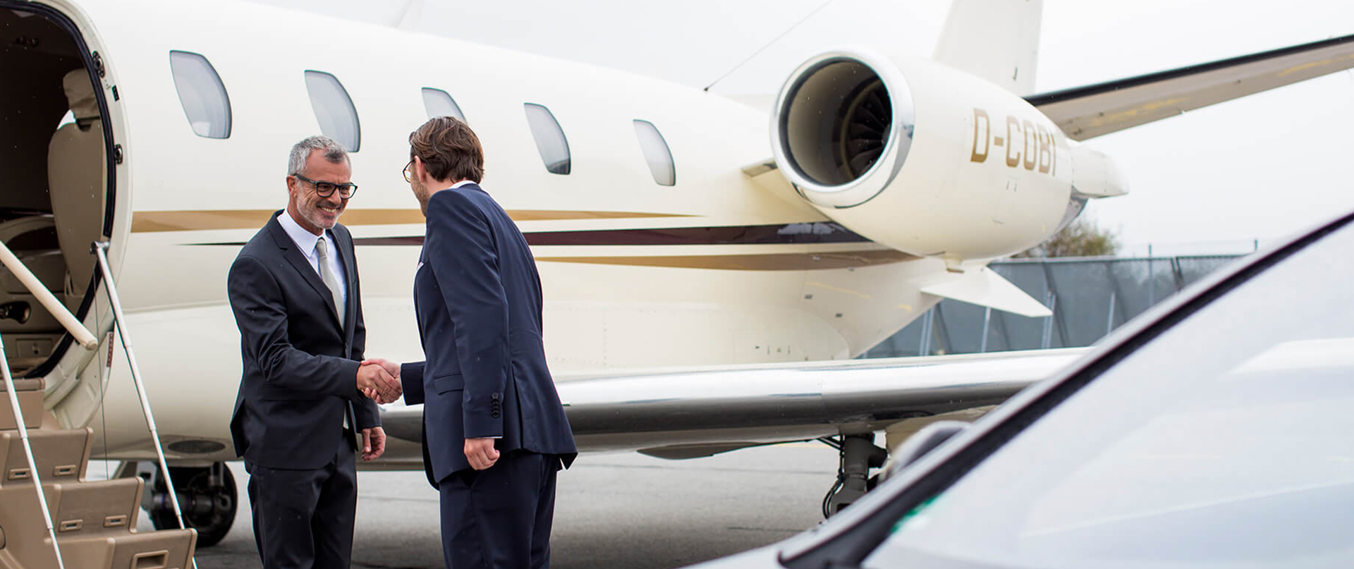 A chauffeur opens the door of an limousine at the airport.